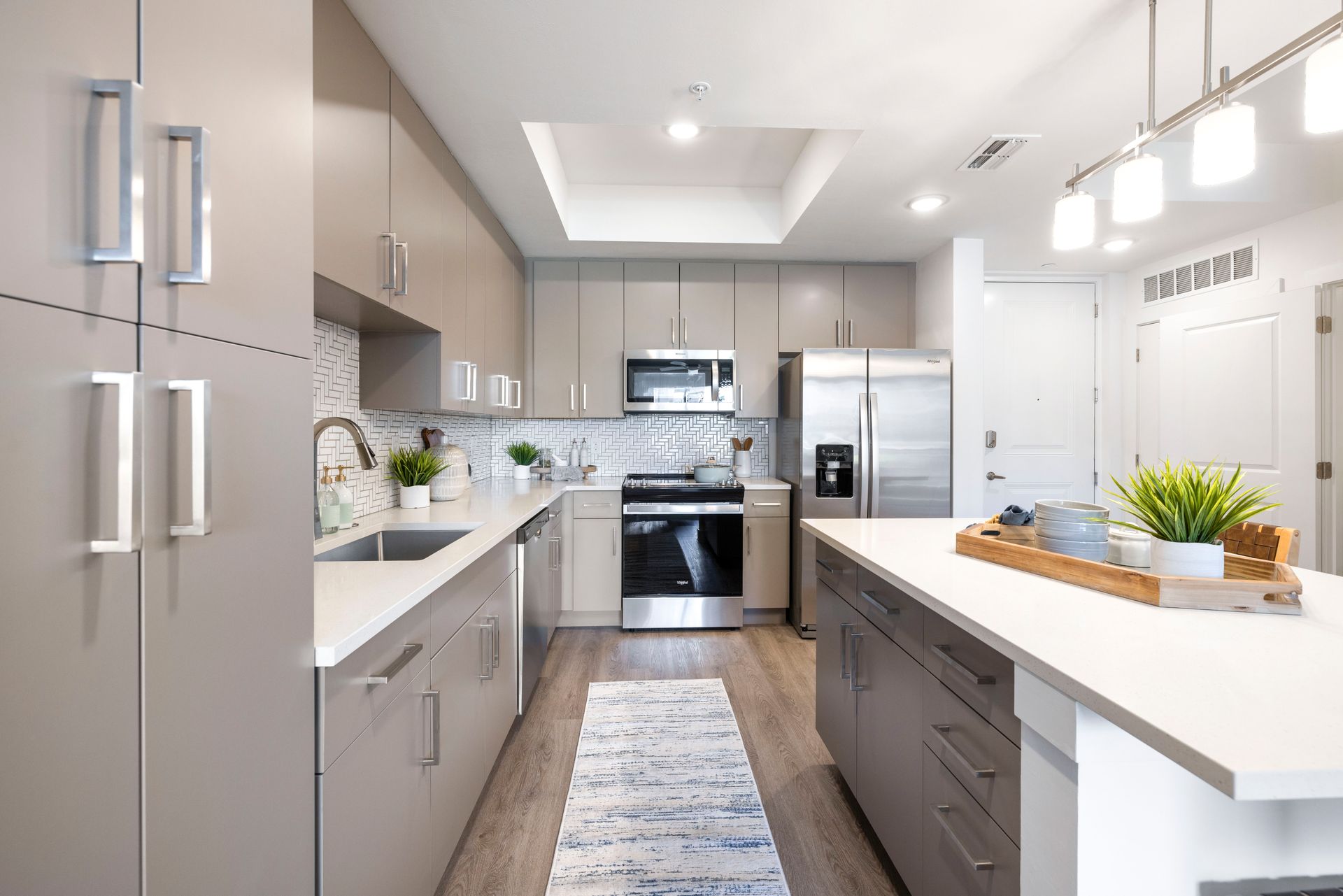 A kitchen with stainless steel appliances , gray cabinets and white counter tops at Corsa at Estero Crossing.