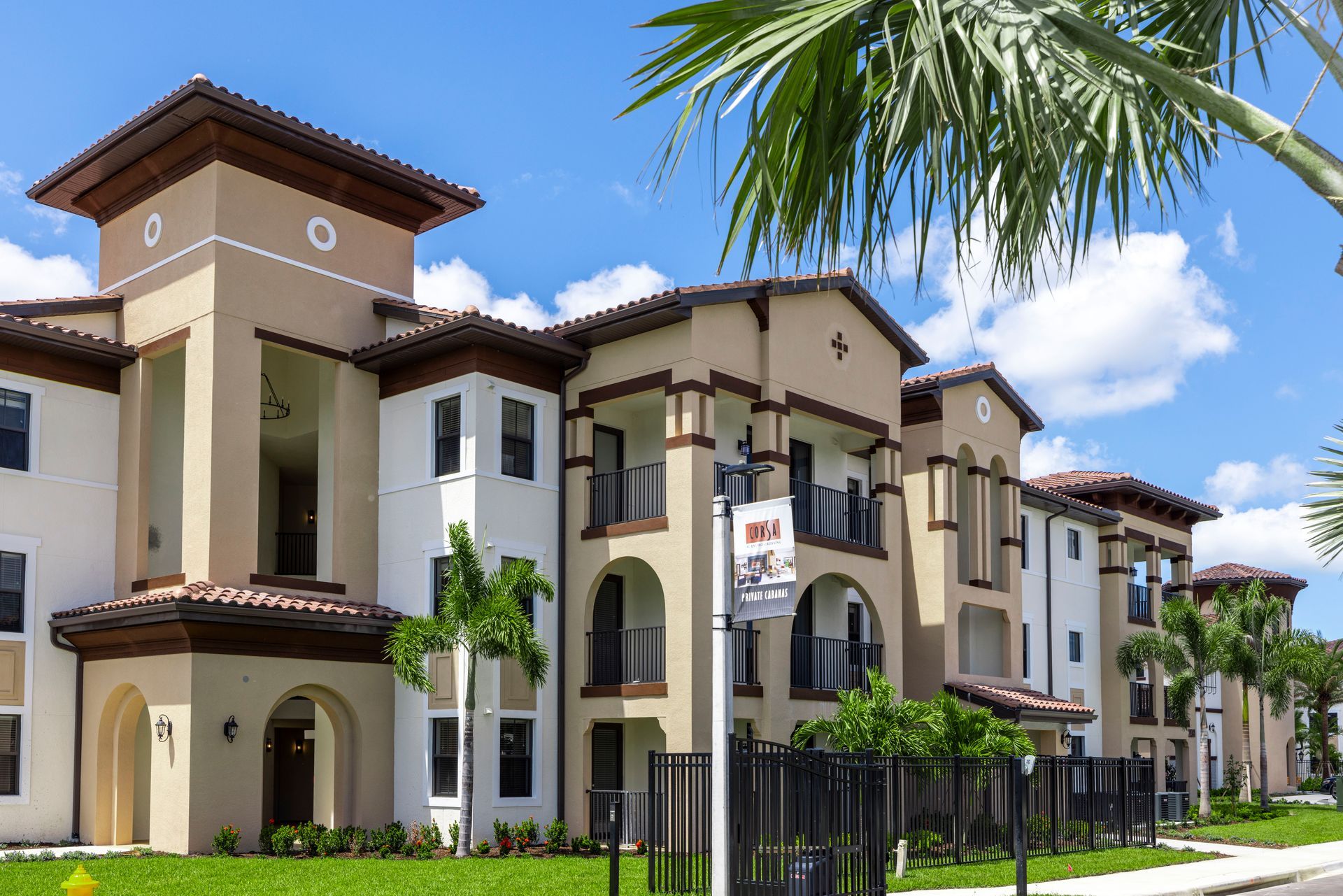 A large apartment building with a palm tree in front of it at Corsa at Estero Crossing.