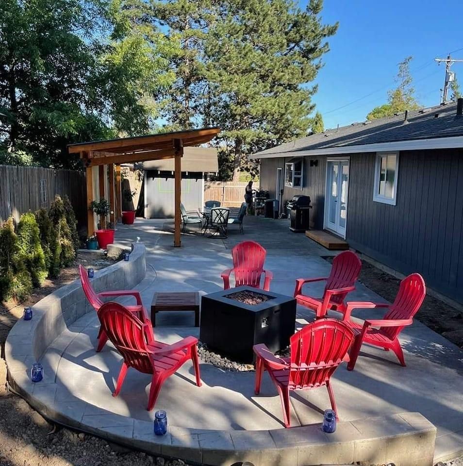 A patio with red chairs and a fire pit in front of a house