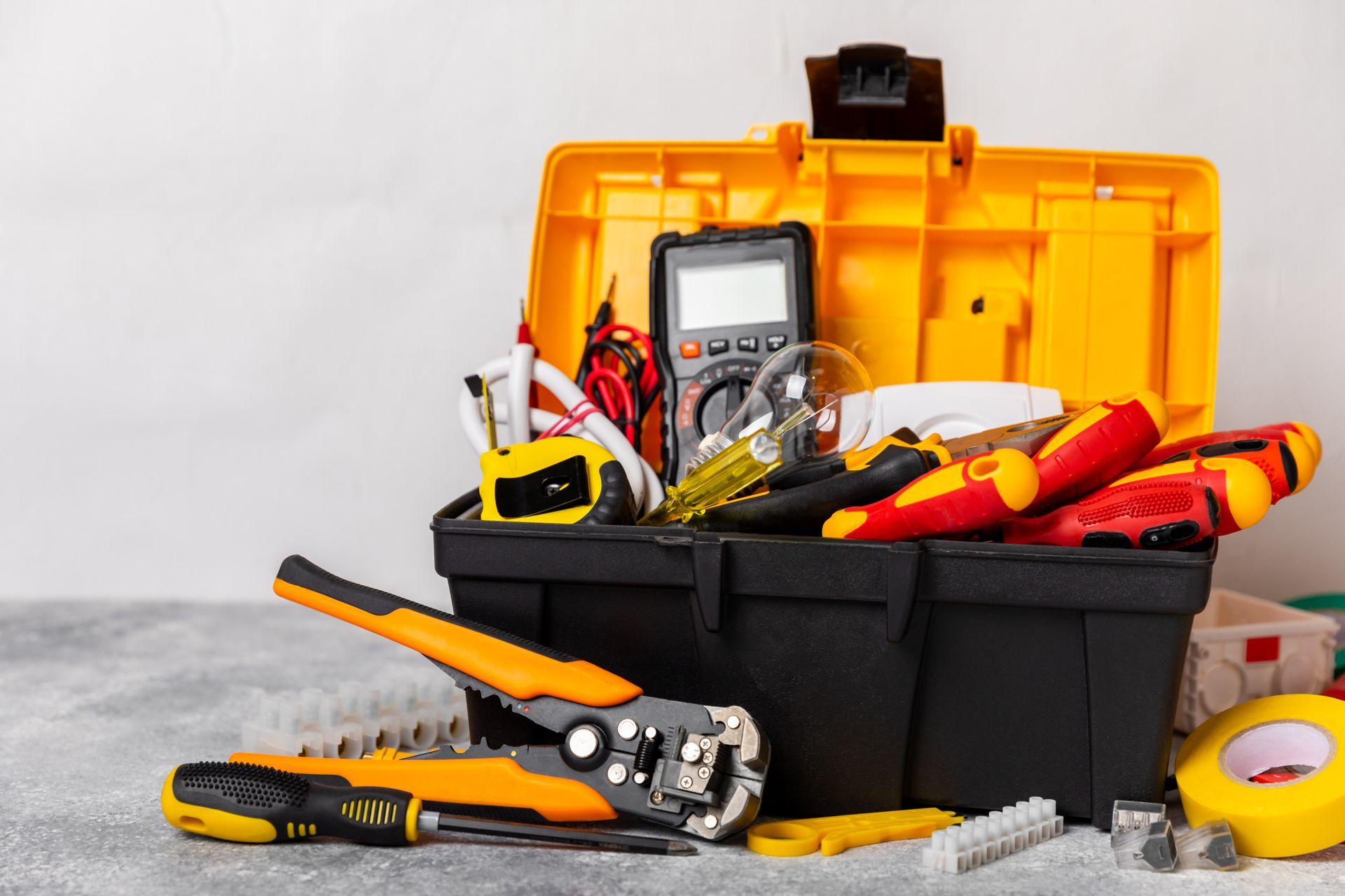 Yellow and black toolbox open, filled with electrical tools including a multimeter, wire strippers, and screwdrivers.
