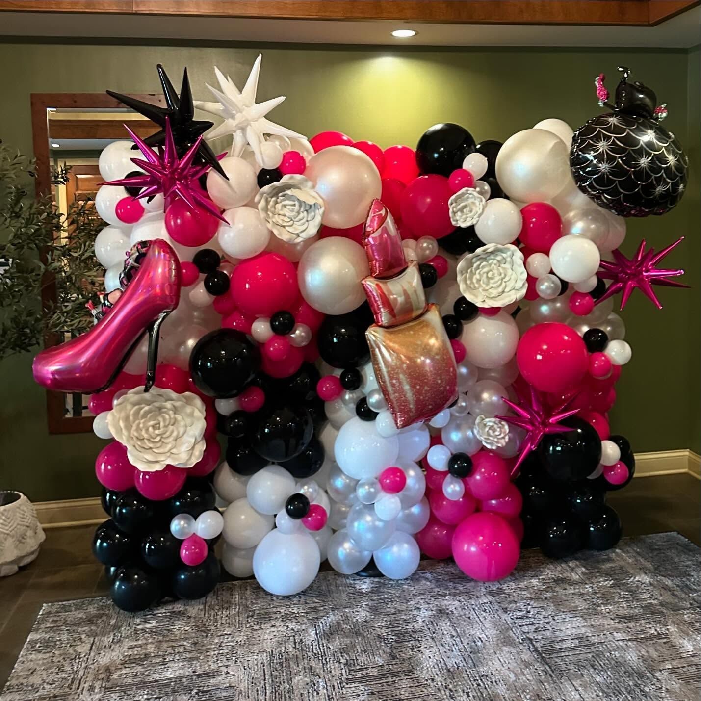 A wall of balloons with a pink shoe in the middle