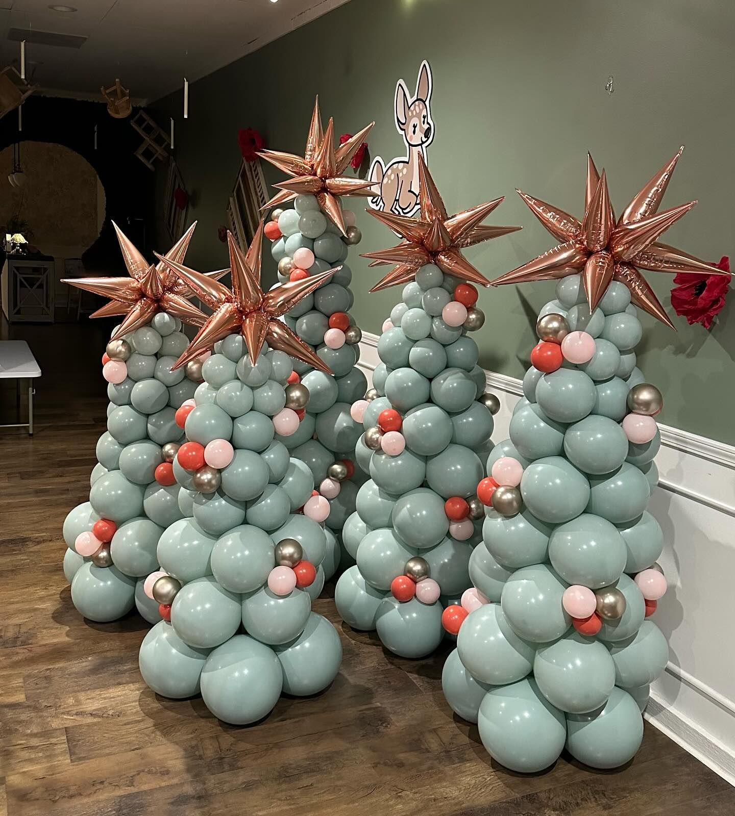 Balloon-covered cone decorations with copper star toppers in a hallway, in pale blue and coral.