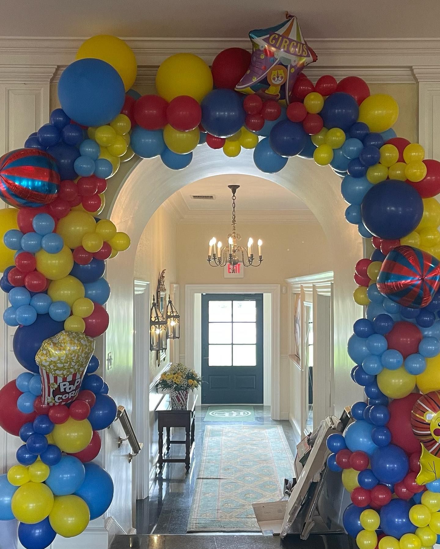 A hallway is decorated with balloons and a chandelier.