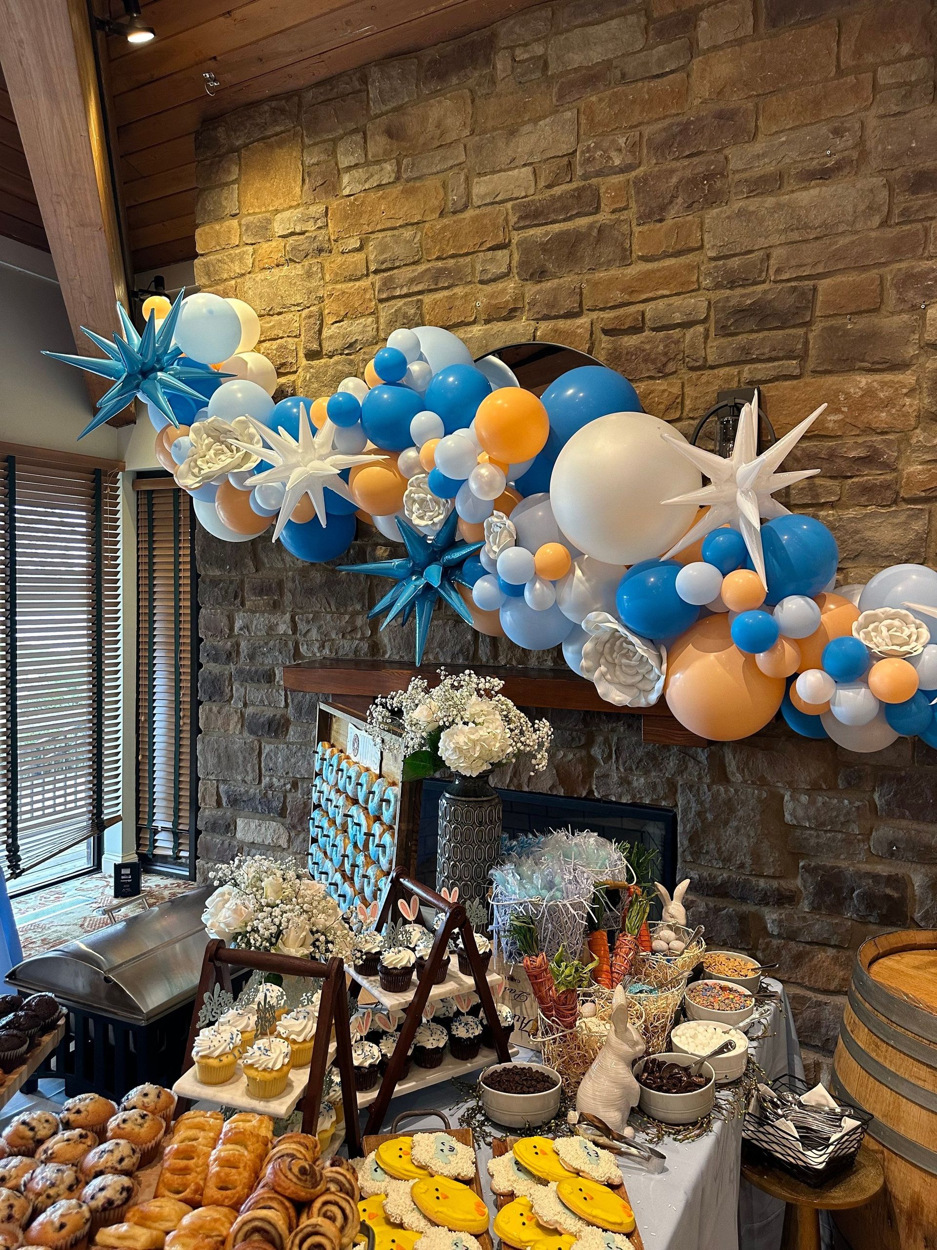 There is a table with a lot of food and balloons on it.
