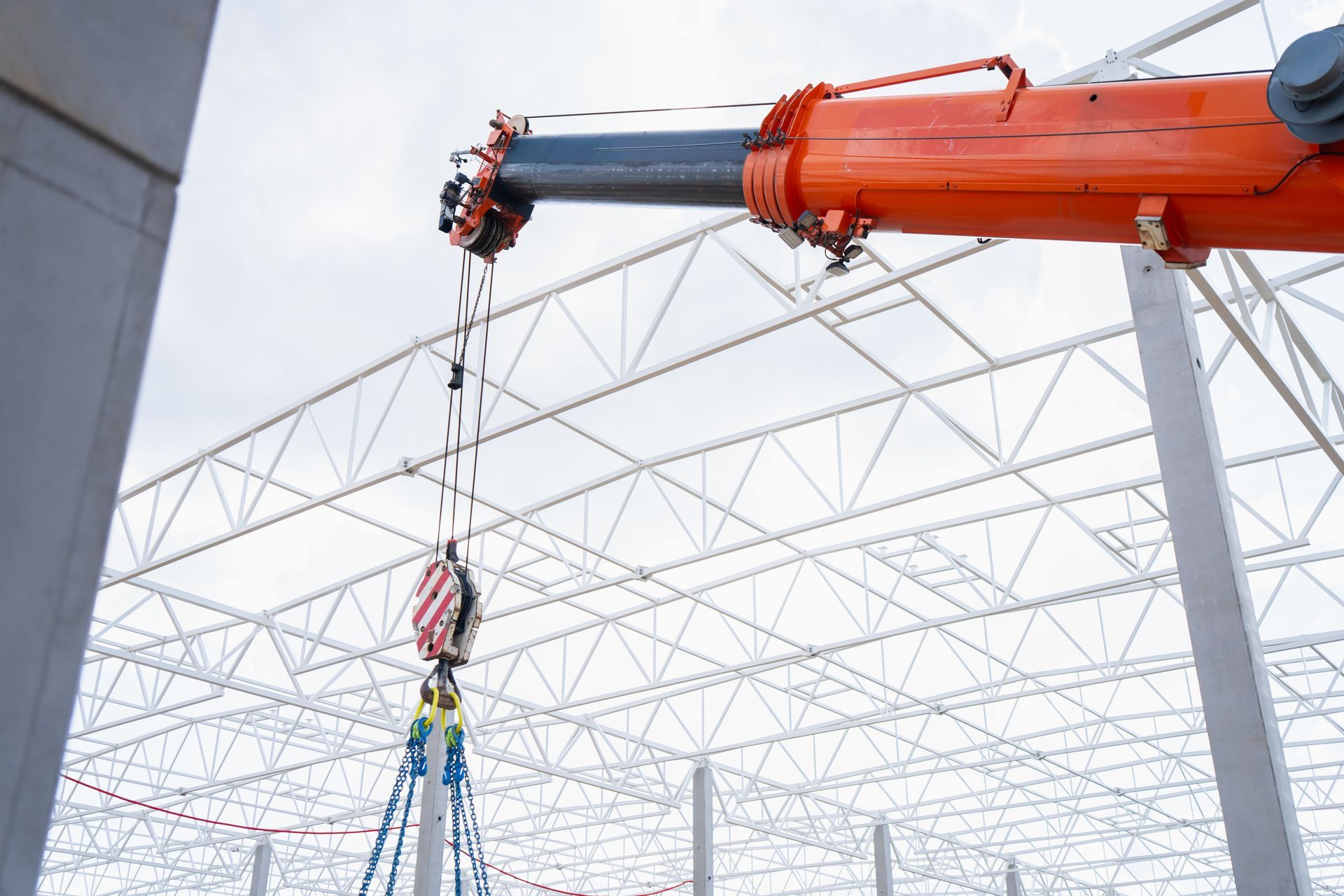 A mobile crane lifting rig suspended below a telescopic boom inside a steel truss frame. A mobile crane lifting rig suspended below a telescopic boom inside a steel truss frame.