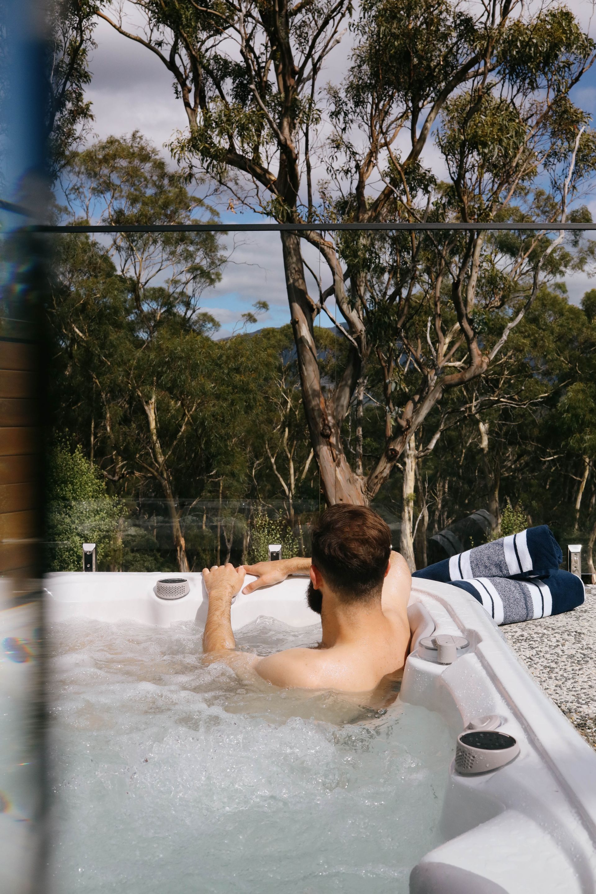 A man is laying in a hot tub with trees in the background.