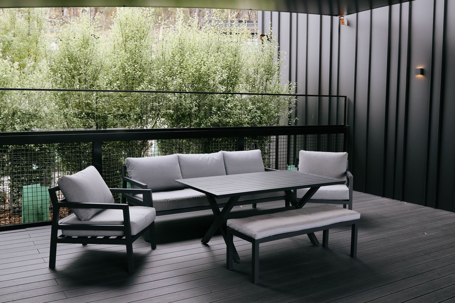 A balcony with a couch , chairs , table and bench.