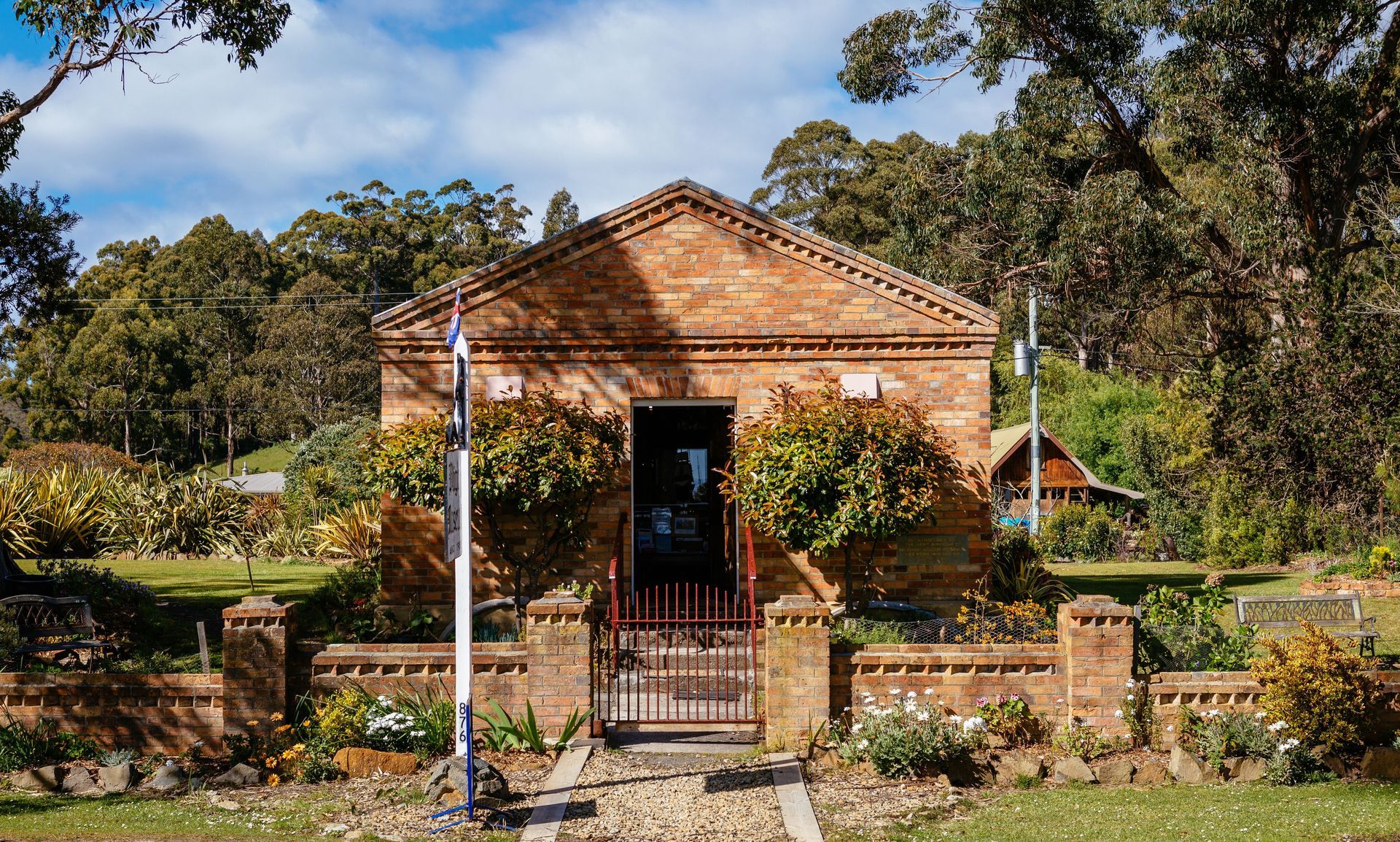 A small brick building with a flag in front of it.