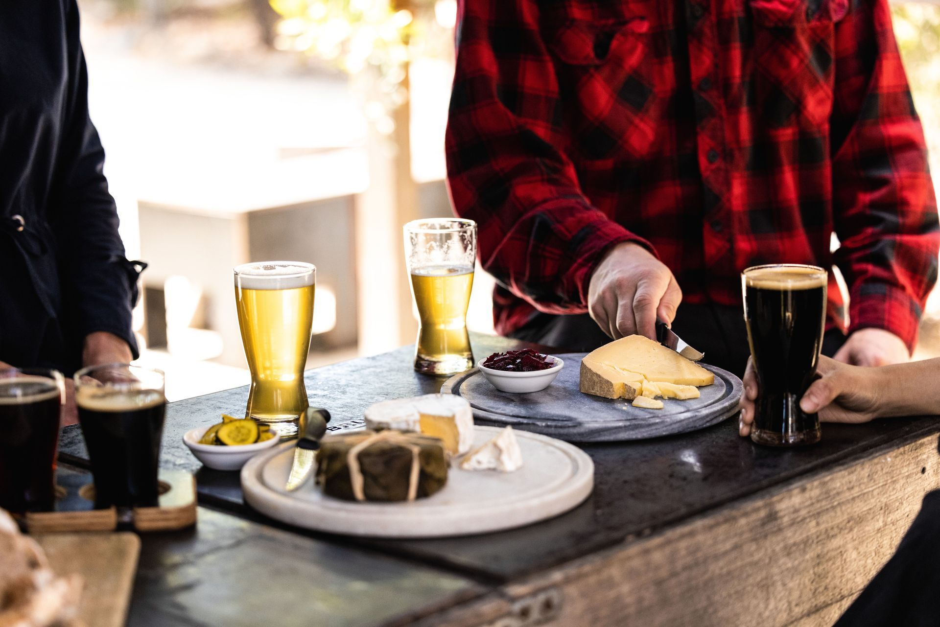 A group of people are sitting at a table eating cheese and drinking beer.