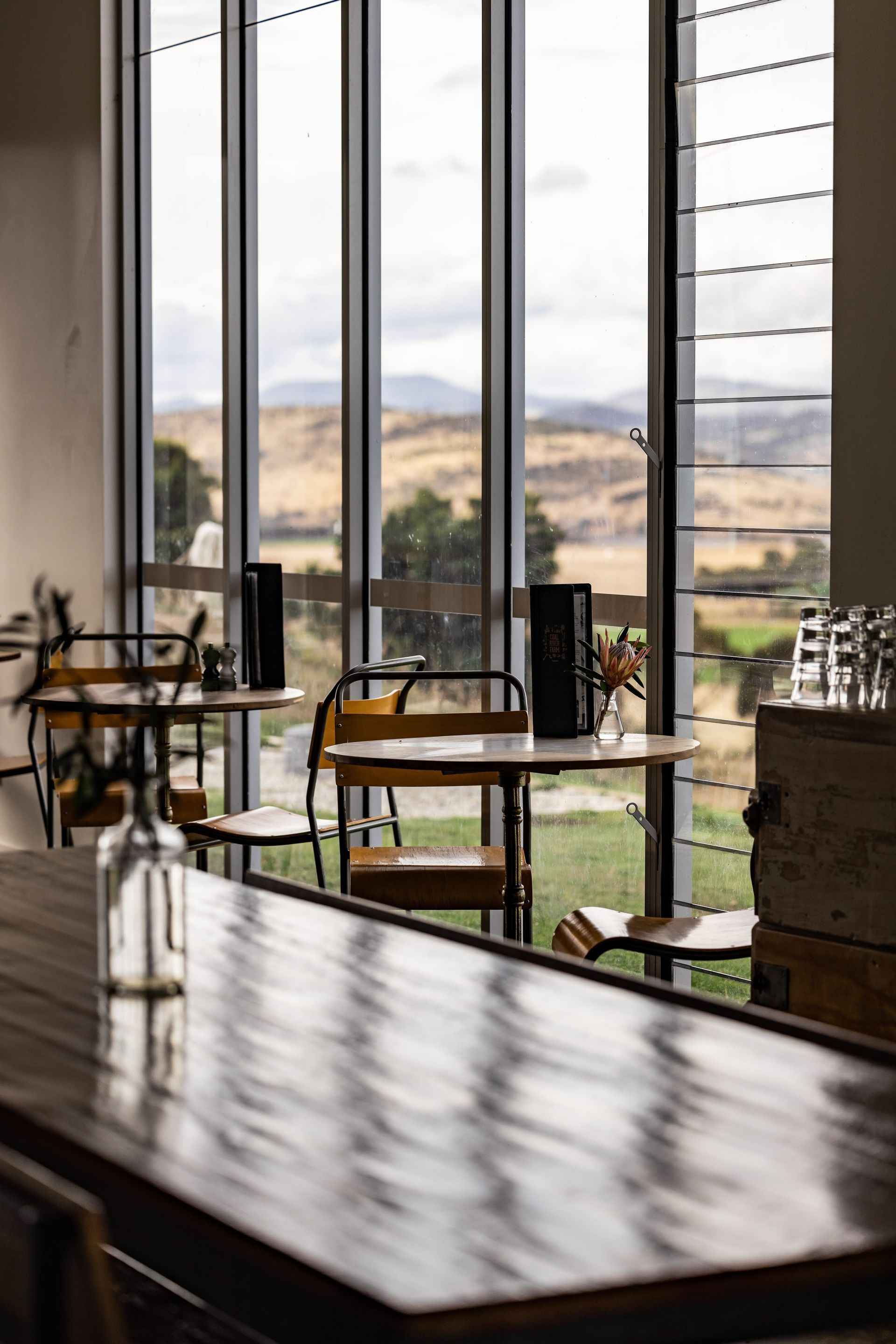 A restaurant with tables and chairs in front of a large window.