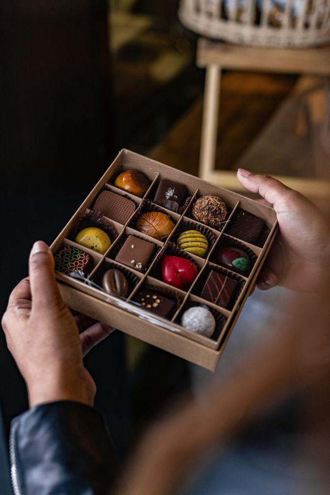 A person is holding a box of chocolates in their hands.