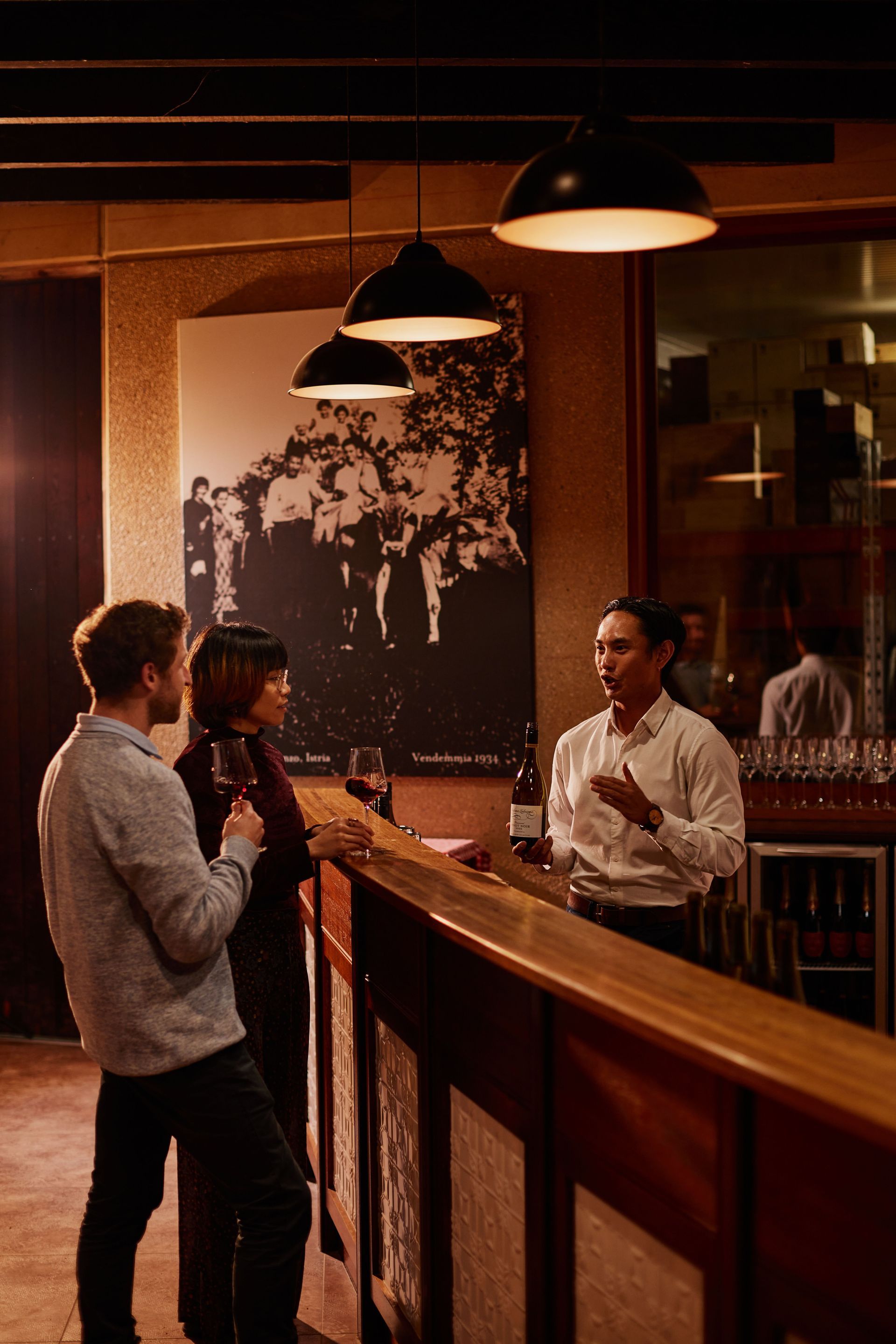 A man and a woman are standing at a bar talking to each other.