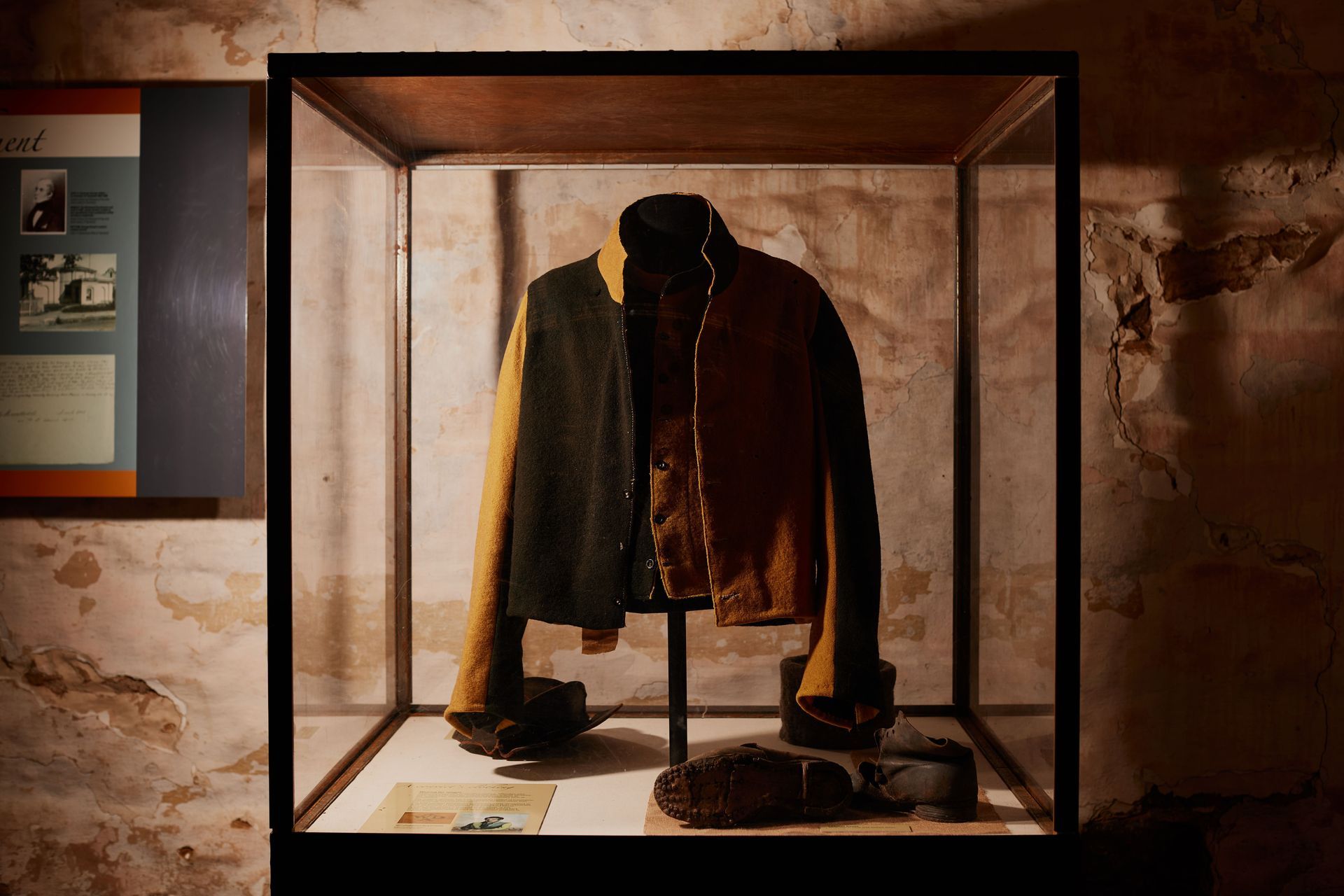 A brown jacket is displayed in a glass case