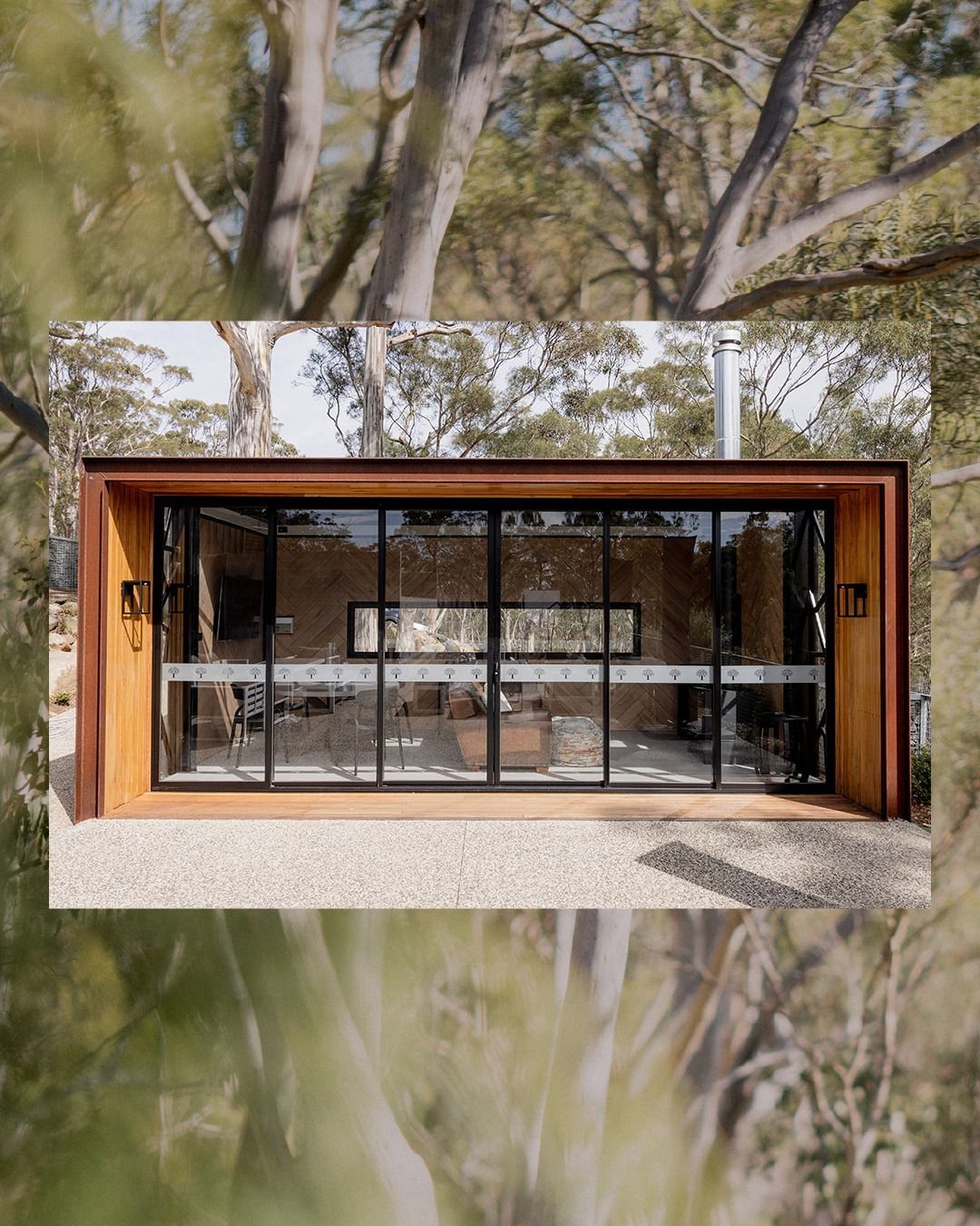 A house with a lot of windows is surrounded by trees.