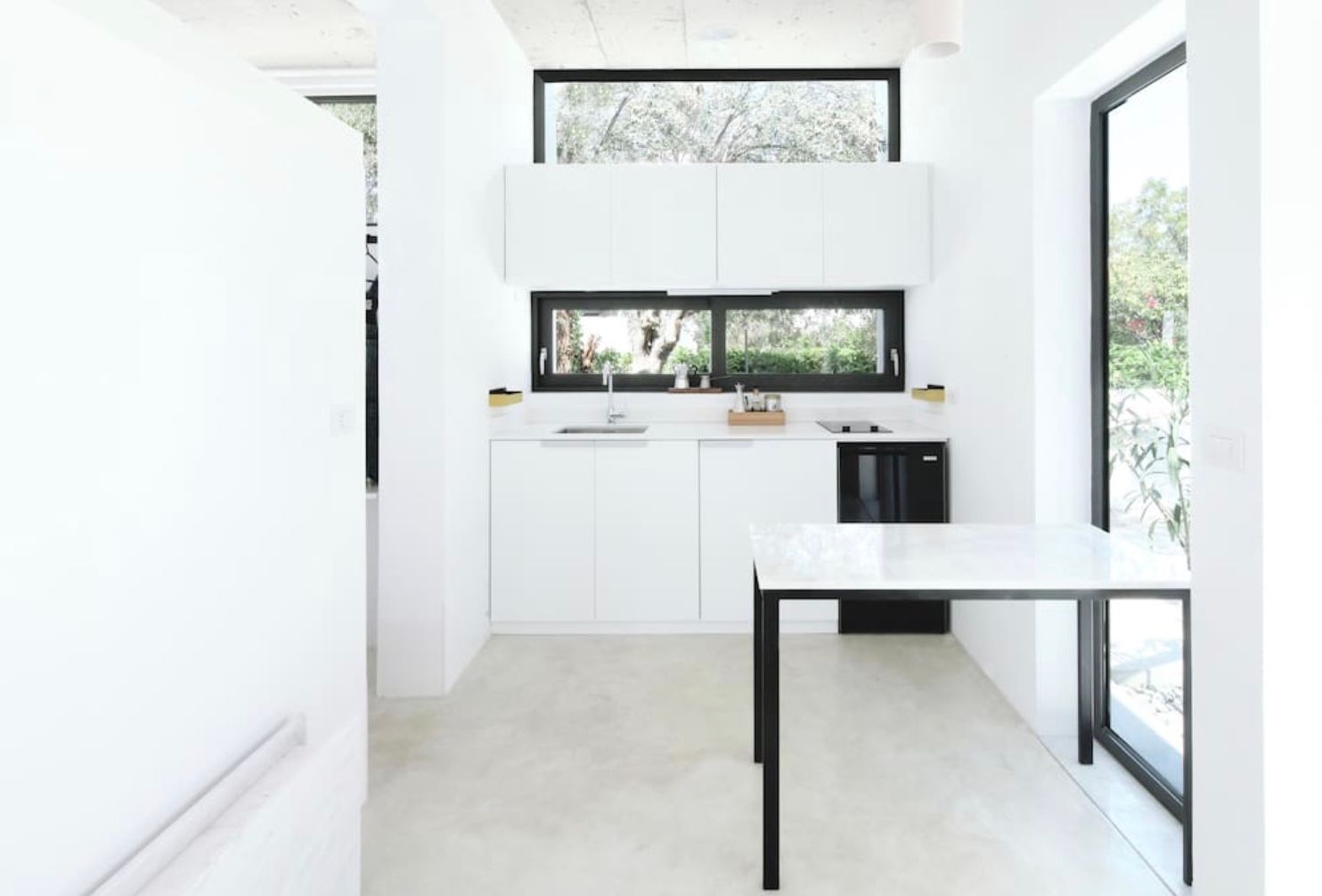 A kitchen with white cabinets and a white table