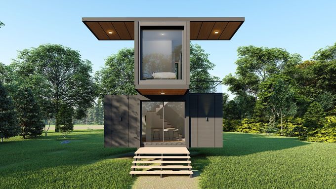 A small house is sitting in the middle of a grassy field surrounded by trees.