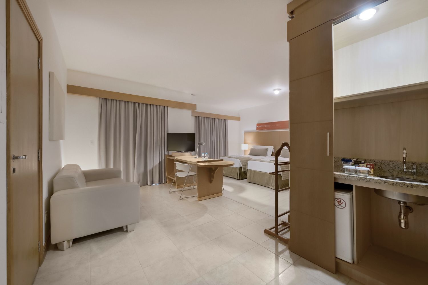 Um quarto de hotel com duas camas, uma mesa, cadeiras e uma pia.