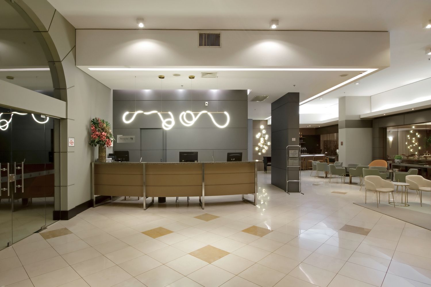 Um lobby de hotel com balcão de recepção e cadeiras.