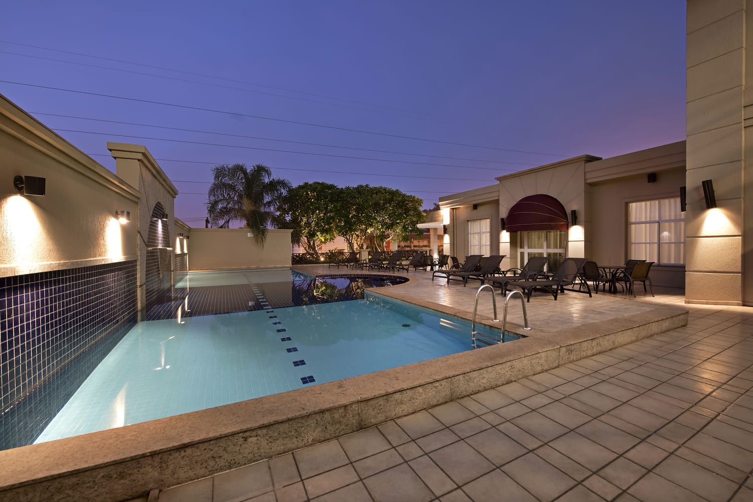 Uma grande piscina é cercada por um edifício à noite