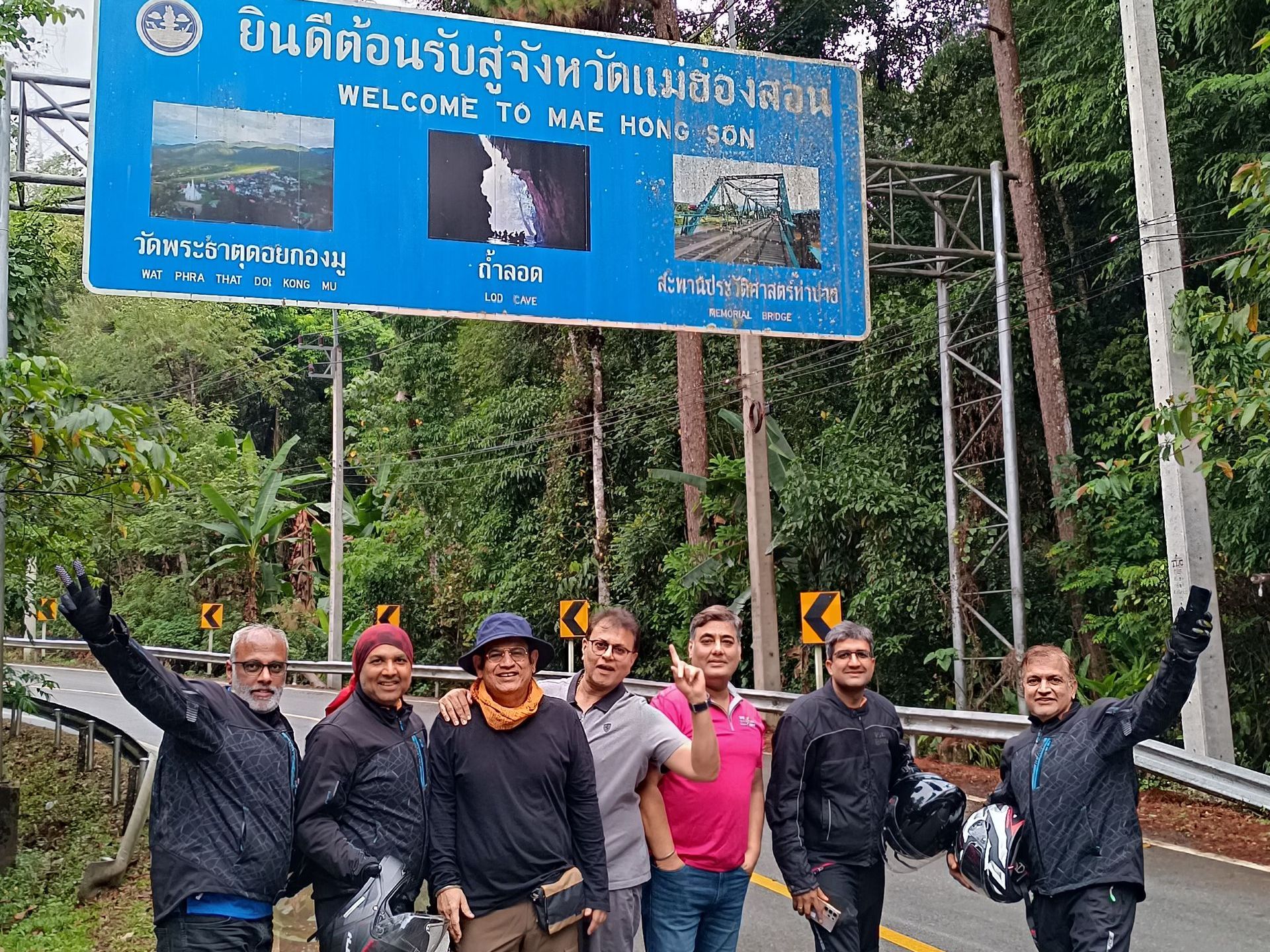 A group of men are standing in front of a sign that says welcome to mail home