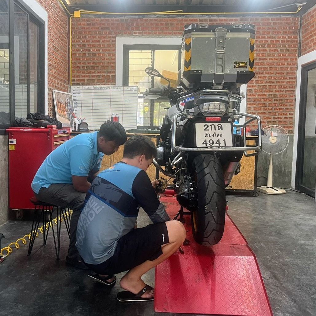 Two men are working on a motorcycle in a garage.