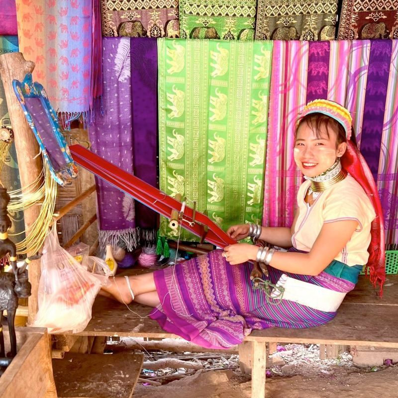 Karen woman weaving traditional textiles on a handloom in a cultural village in Northern Thailand”
