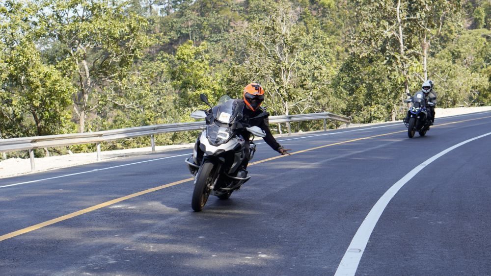 Adventure motorcycle riders leaning through a mountain curve in Northern Thailand during a guided tour
