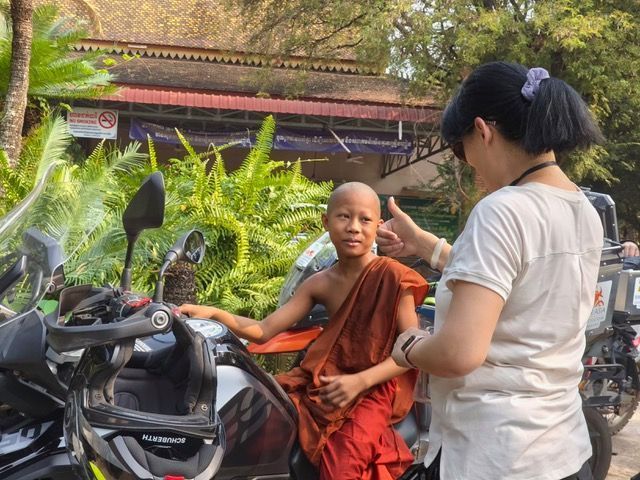 Local monk talking with a traveler beside a BMW adventure motorcycle in Luang Prabang