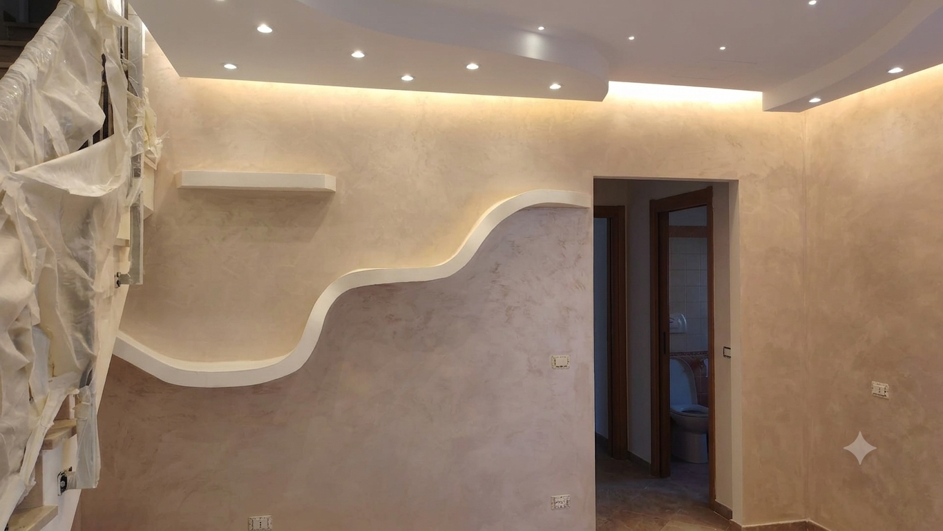 Soggiorno vuoto color beige con nicchia a muro curva, faretti a incasso a soffitto e porta aperta.