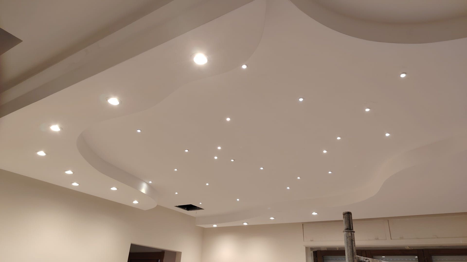Soffitto bianco incassato con numerosi piccoli faretti in una stanza moderna