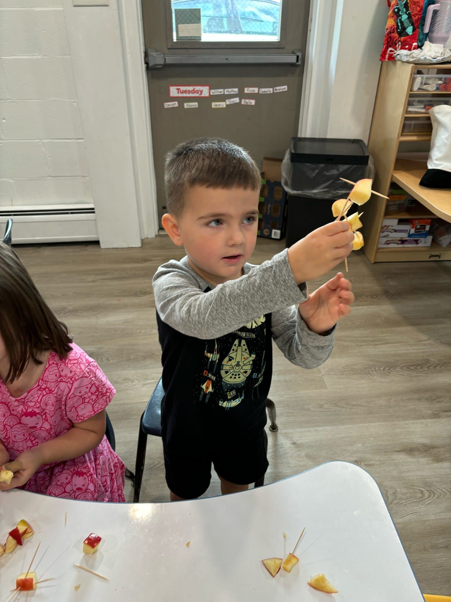 A young boy is holding a piece of fruit on a stick.