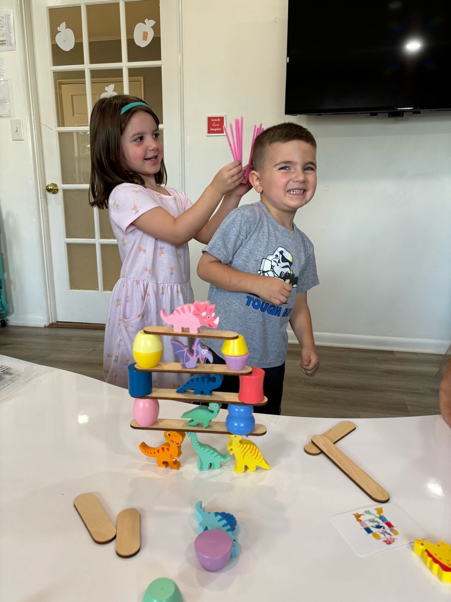 A boy and a girl are playing with toys on a table.