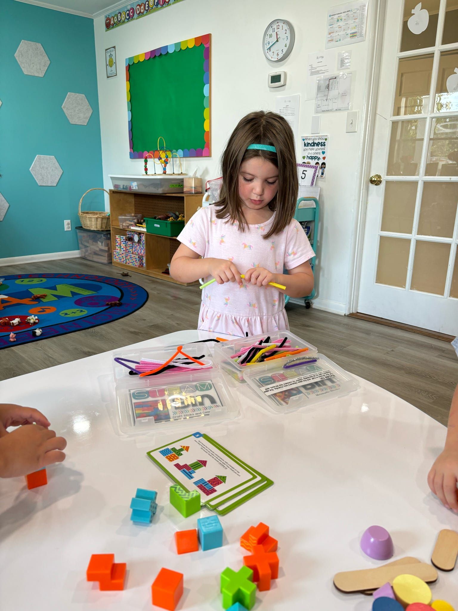 A little girl is sitting at a table playing with toys.