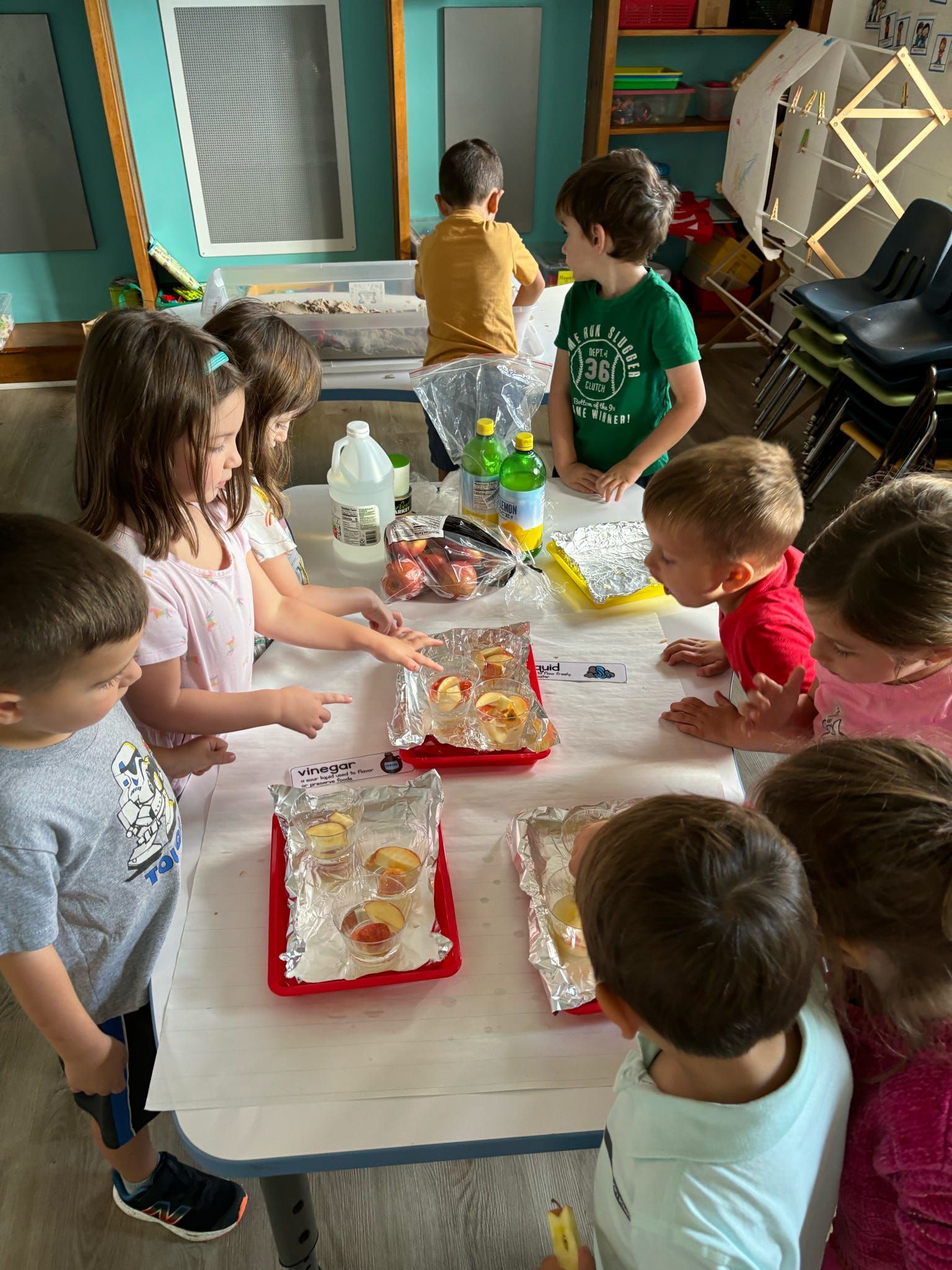 A group of children are standing around a table.