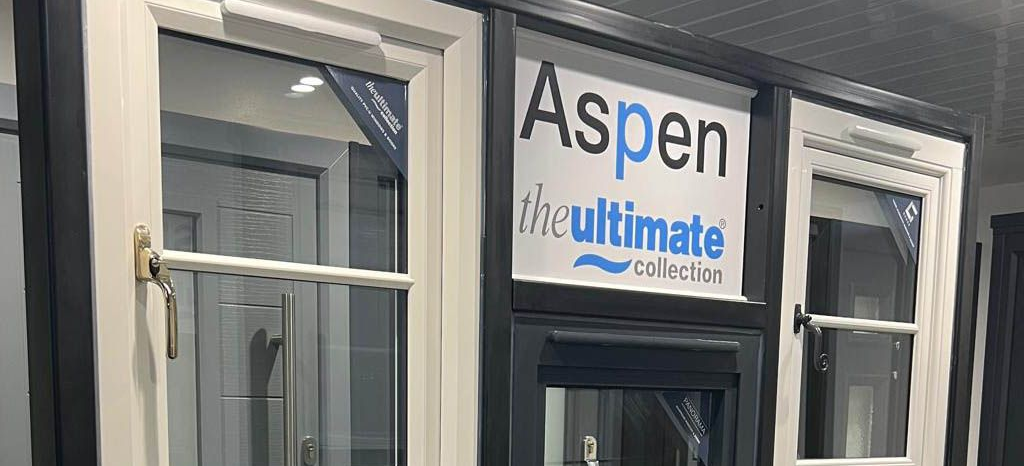 Aspen Ultimate window display with white-trimmed windows and a central door on a gray storefront