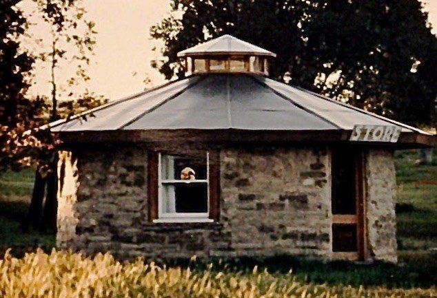 Small stone house with a metal roof in a grassy yard at dusk