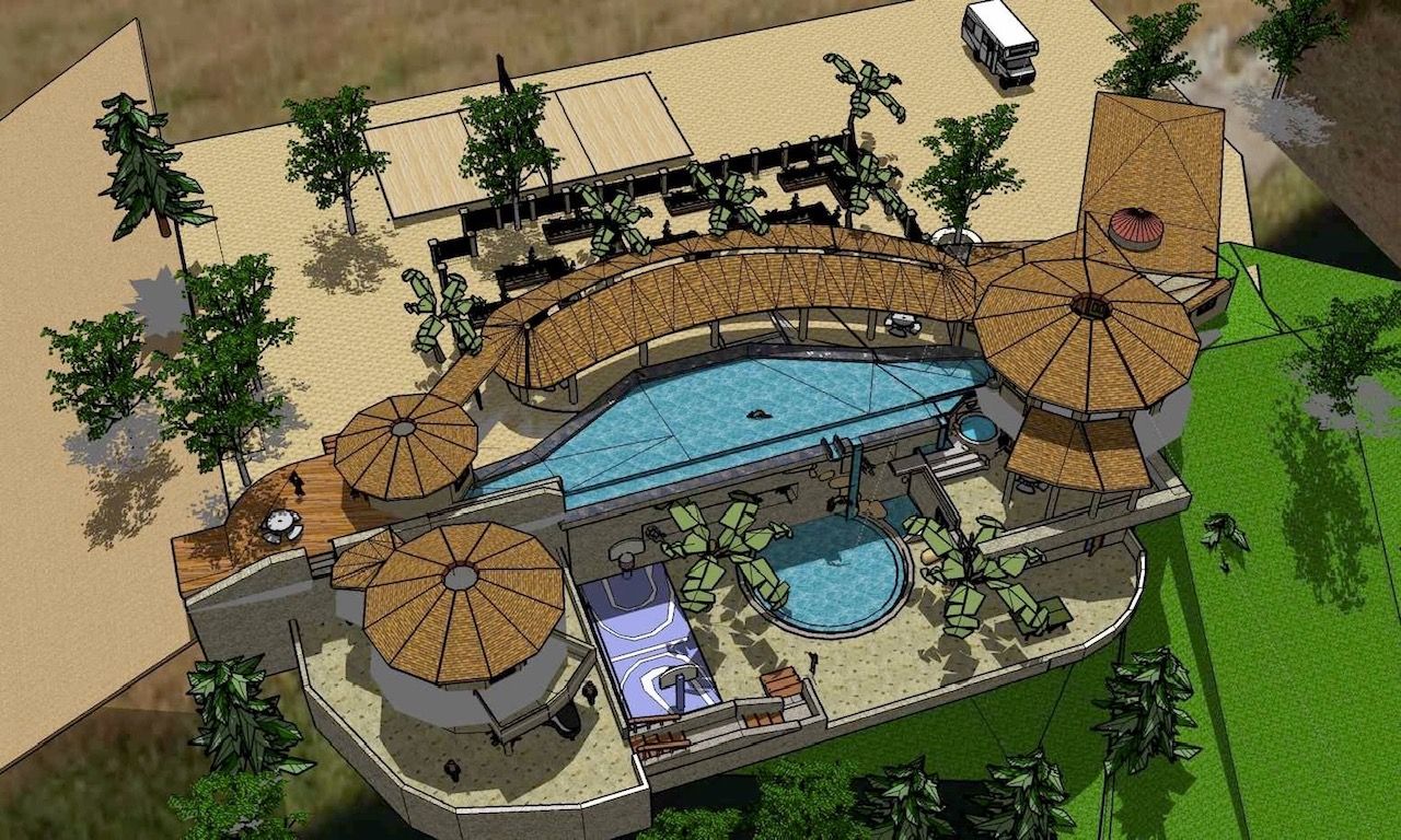 Aerial view of a resort pool area with curved swimming pools, lounge chairs, umbrellas, and palm trees.