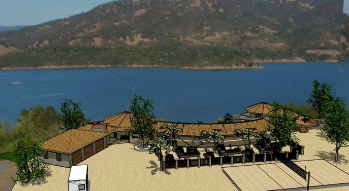 Lakeside resort with tan buildings, palm trees, and a mountain across the blue water