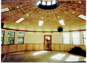 Empty round room with a domed wood ceiling, windows, and sunlight on the floor.