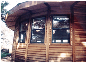Wooden cabin exterior with bay windows and a curved roof overhang