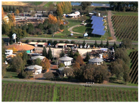 Aerial view of a rural farmstead with fields, trees, and several buildings in autumn colors