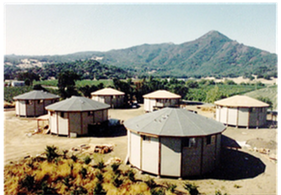 Round huts in a rural landscape with mountains in the background
