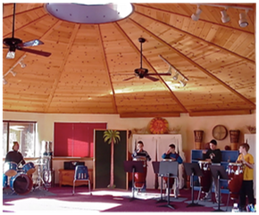 Band rehearsing in a wood-paneled room with a domed ceiling and instruments set up around the space