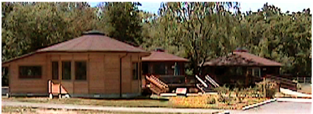 Single-story brick building with a brown roof, surrounded by trees and a walkway
