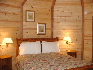 Cozy wooden bedroom with a bed, floral bedspread, and two lit bedside lamps