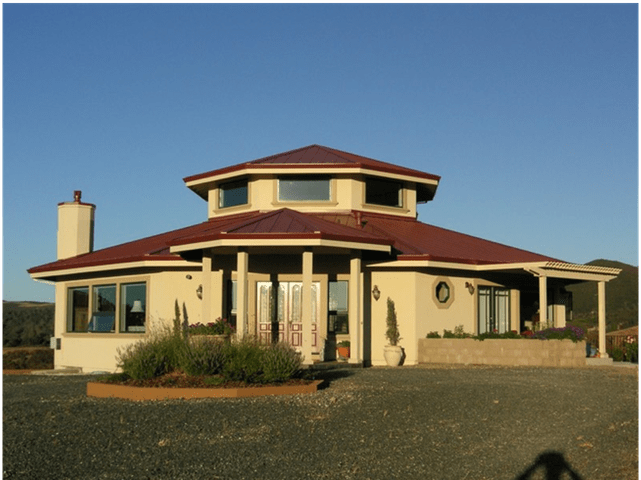 Single-story beige house with a red roof and large windows under a clear blue sky