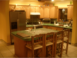 Warm kitchen with wooden cabinets, stainless fridge, and a central island with bar stools.