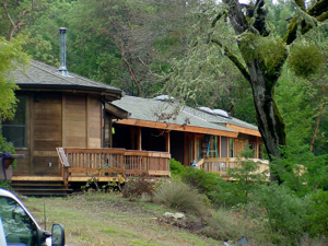 Rustic wooden cabin with porch in a wooded hillside setting