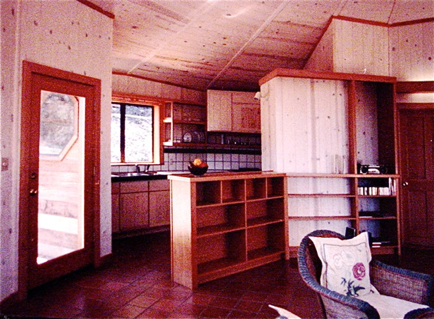 Cozy kitchen interior with wood cabinets, red trim, tiled backsplash, and a large windowed door