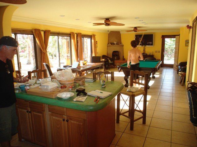 Spacious kitchen and game room with a pool table, island counter, bar stools, and large windows.